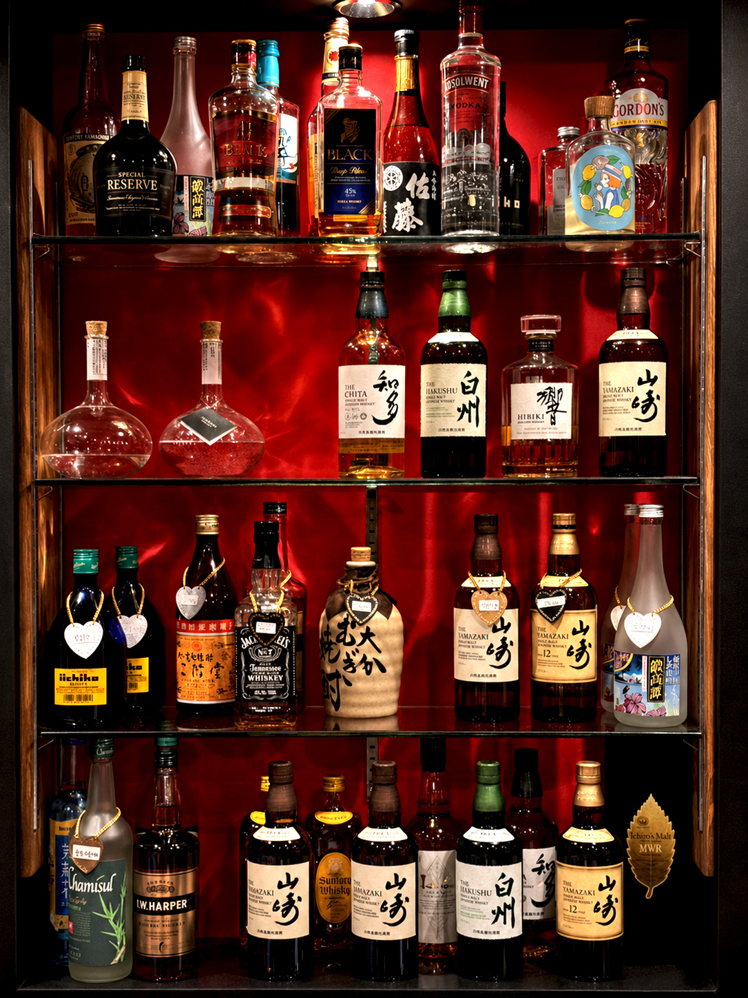 赤い背景に並ぶウイスキーや焼酎のボトル棚